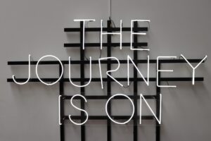 Una scritta al neon che dice "The journey is on"